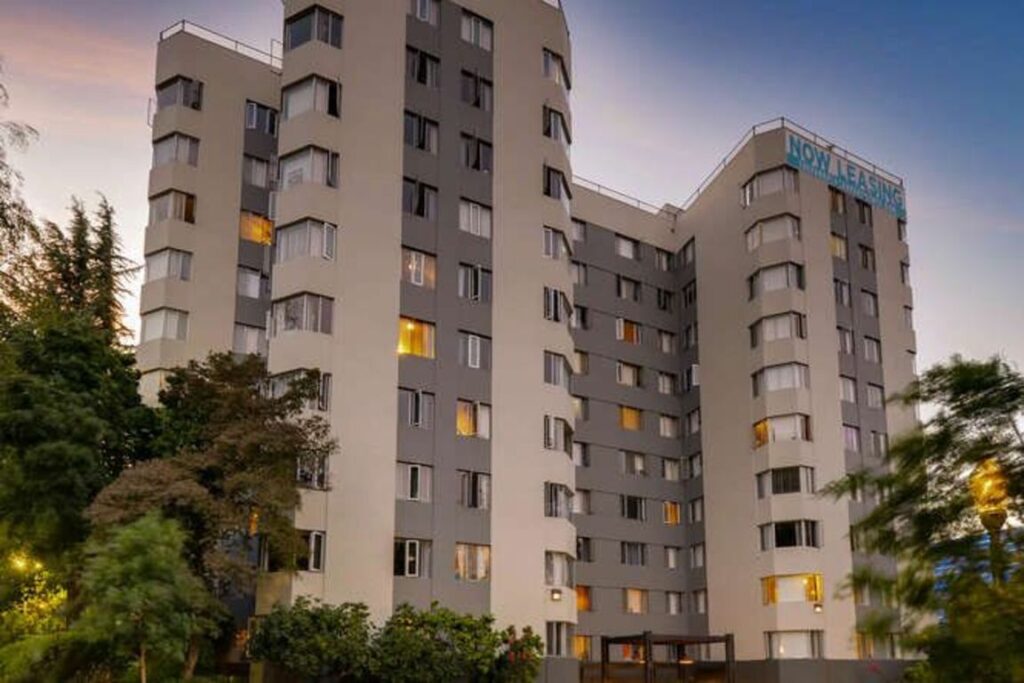 Building exterior. Tall boxy building with 10 floors surrounded by trees